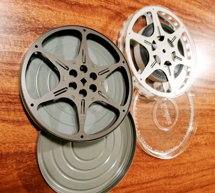 Two 16mm film cans and reels from 1960s. One Of Them Has A Colored Movie.