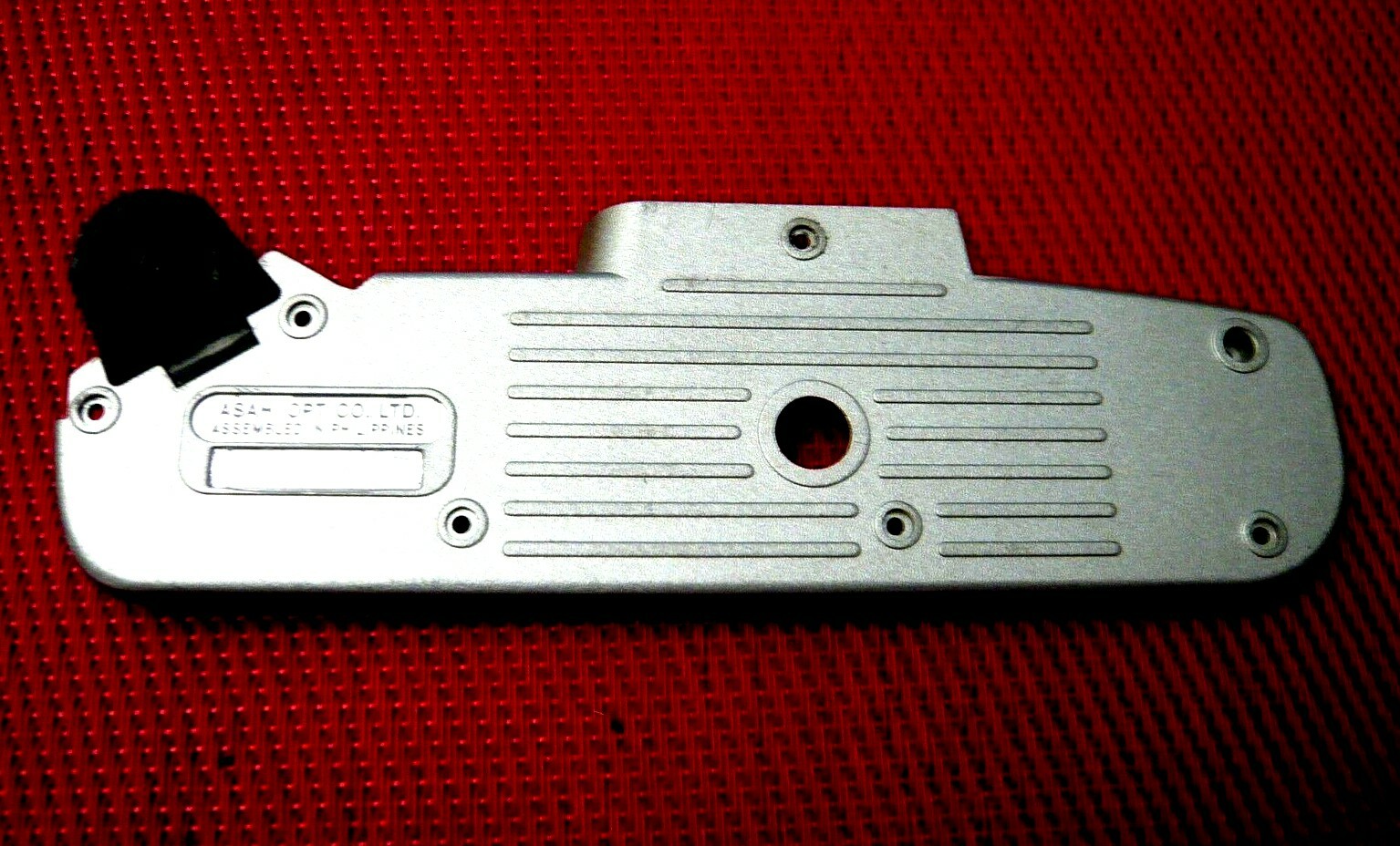Bottom plate with battery door for Pentax ZX 10 camera.
