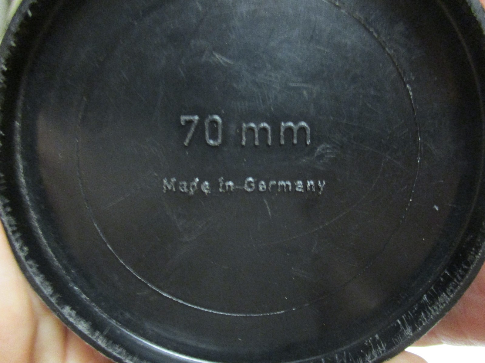 Black plasic push on 70mm lens cap. Made in Germany