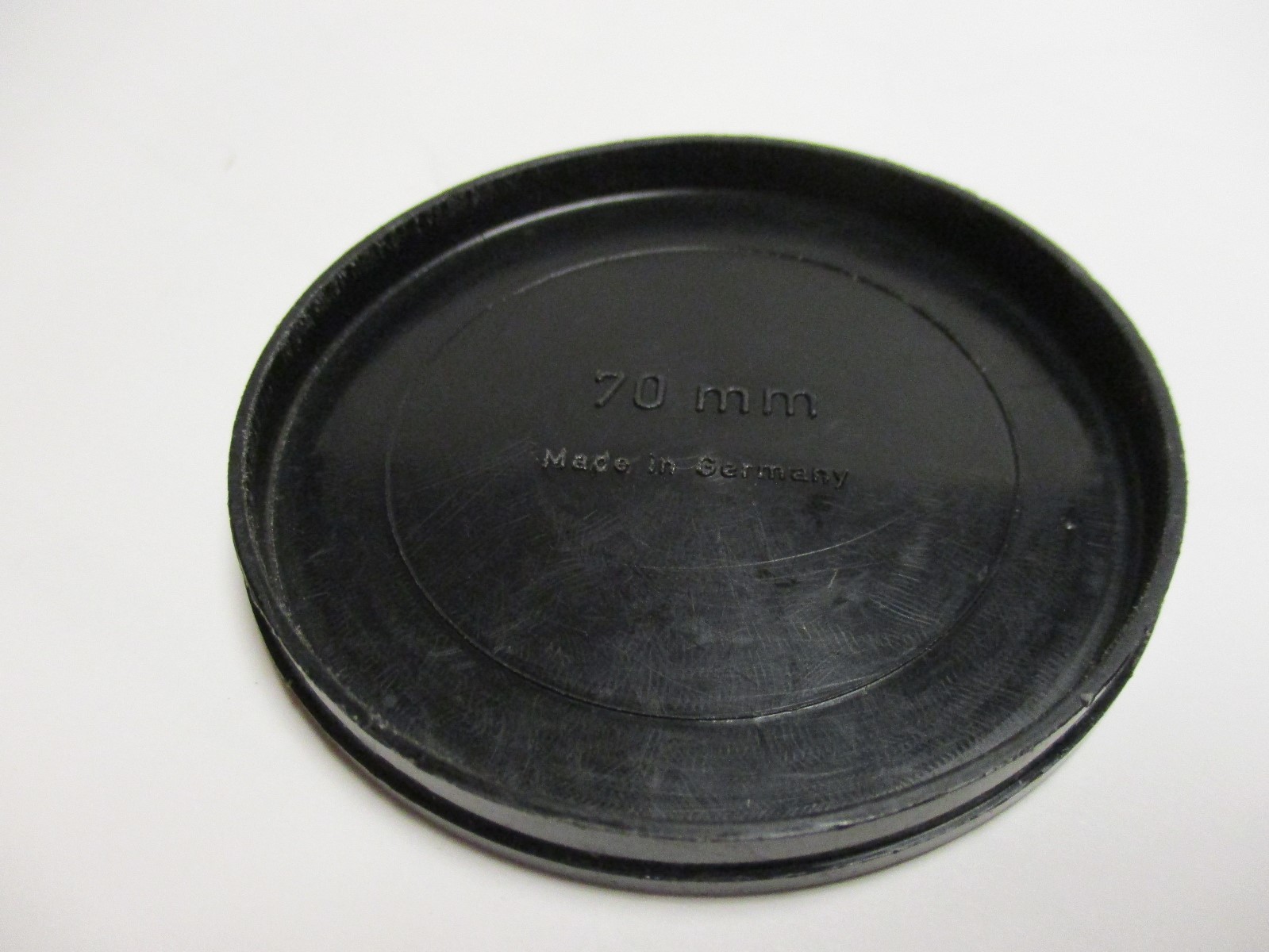 Black plasic push on 70mm lens cap. Made in Germany